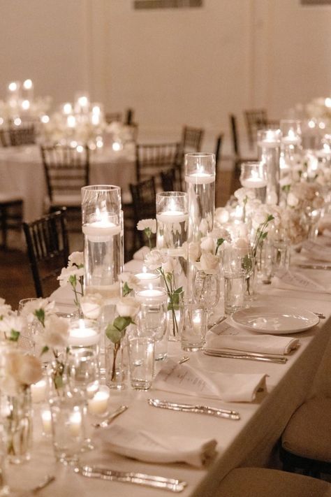 A stunning reception setup featuring delicate white florals and glowing candlelight, creating an atmosphere of romance and sophistication. Perfect for a timeless wedding celebration. #CandlelitWedding #ElegantReception #WhiteFlorals #RomanticAmbiance #WeddingInspiration Candlelit Wedding Ceremony Indoor, White Candle Lit Wedding, White And Candle Wedding, Wedding Round Table Candles, Candle Decor For Weddings, Reception Set Up, Classy Indoor Wedding, Wedding Table With Candles, Candle Tablescapes Wedding