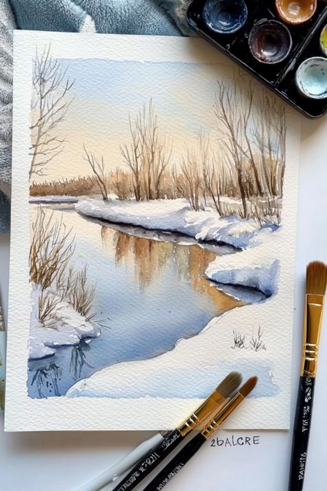 A serene winter watercolor painting of a river with snowy banks and bare trees, surrounded by art supplies. Winter Scenes Watercolor, Winter Painting Watercolor, Winter Scenes Paintings, Winter Watercolor Landscape, Snowy Landscape Painting, Winter Watercolor Simple, Snow Scenes Winter Landscape, Watercolor Snow Scenes, Watercolor Winter Scenes