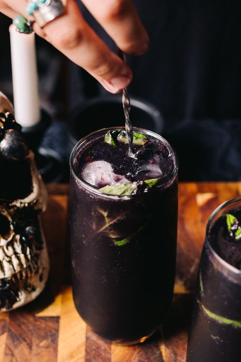 This Midnight in the Witch’s Garden Cocktail (Sugar Free) and the perfect spooky drink for your Halloween party! Activated charcoal and blueberries give this drink a creepy, black and purple hue. Combine with gin, fresh lemon juice, muddled basil leaves, and ginger beer for a refreshing botanical drink. Enjoy these drinks that look like they came straight from a witch’s garden at midnight this Halloween! #AFullLiving #KetoCocktails #HalloweenRecipes #HalloweenCocktails #SpookyCocktails Midnight In The Witches Garden, Halloween Beer Drinks, Viking Themed Cocktail, Goth Alcoholic Drinks, Scapegrace Black Gin, Activated Charcoal Cocktail, Witch Themed Drinks, Frogs Breath Drink, Witchy Alcoholic Drinks