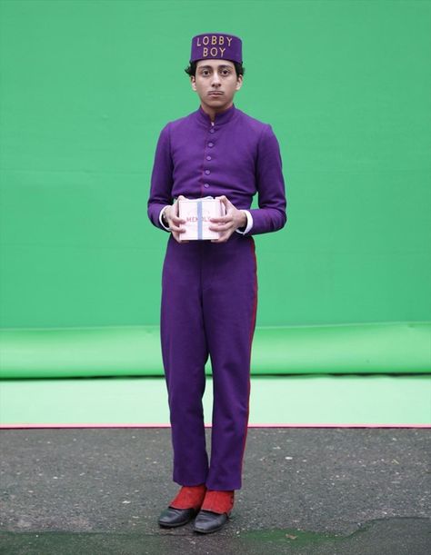 Tony Revolori as Zero, standing in front of a green screen, Mendl’s box in hand | The Grand Budapest Hotel Zero The Grand Budapest Hotel, Zero Grand Budapest Hotel, Wes Anderson Green, Grand Budapest Hotel Book, Wes Anderson Book, Wes Anderson Characters, Tony Revolori, Wes Anderson Aesthetic, Lobby Boy