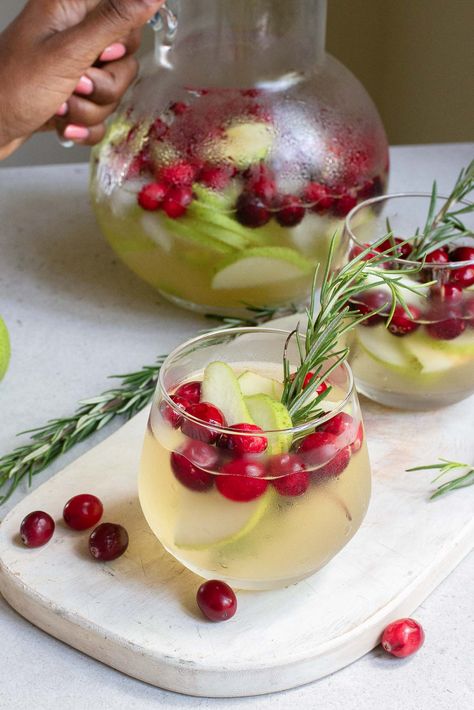 Get ready to make your holiday gatherings memorable with our easy Christmas Sangria! This white wine cocktail is packed with the merry flavors of cranberries, apple and pear, a splash of ginger beer, and star anise. It’s absolutely perfect for entertaining a crowd. Just mix up a large batch of this delicious sangria and watch as your guests enjoy each festive sip .Grab your pitchers and get ready for toasts all around! #ChristmasSangria #HolidayCheers #FestiveDrinks Easy Christmas Sangria Recipes, Christmas Party Batch Cocktails, Christmas Drinks Pitcher, Holiday Alcoholic Drinks Pitcher, Holiday Sangria Christmas, Christmas Pitcher Drinks, Christmas Margaritas For A Crowd, Christmas Big Batch Cocktails, Grinch Sangria