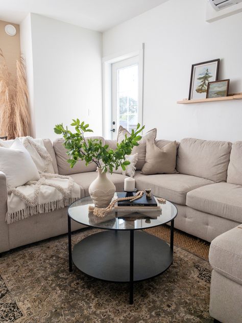 The fresh greenery is everything. I love the way it elevates the space. Styling a round coffee table can be difficult, but a few books, a candle and a vase of fresh greens makes the styling look effortless. In this space I enjoy combining various textures and neutral tones and then grounding it with a patterned rug. Finish it off with a picture ledge featuring two vintage art pieces and the space is complete! Style A Coffee Table, Drop In Bathtub, Round Glass Coffee Table, Large Sectional, Patterned Rug, Picture Ledge, Sofa Fabric, Beige Sofa, Table Styling