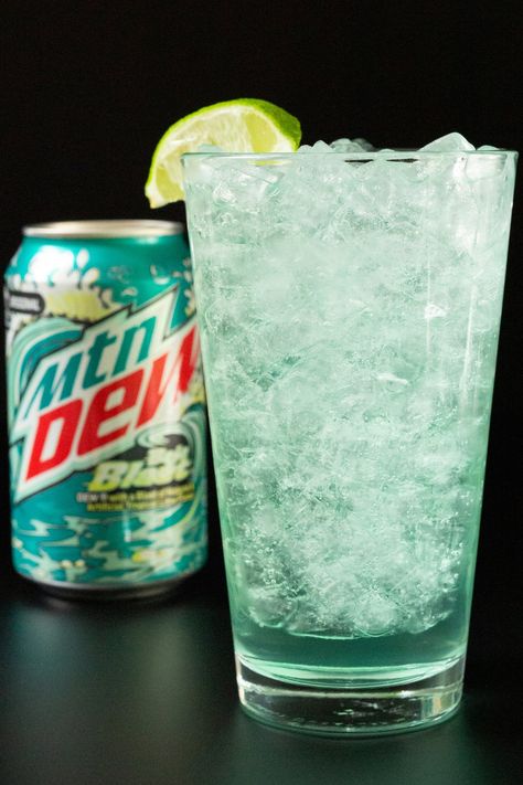 A pint glass filled with pebble ice and a turquoise colored cocktail. A can of Baja Blast is out of focus in the background. Baja Blast Margarita, Baja Blast Cocktail, Taco Bell Drinks, Mtn Dew Baja Blast, Mountain Dew Baja Blast, Iced Caramel Macchiato Recipe, Banana Dog Treat Recipe, Homemade Crunchwrap, Passion Tea Lemonade