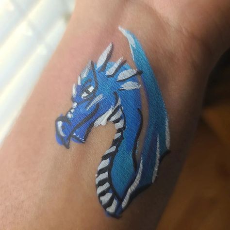 simple blue dragon face paint on arm Face Paint On Arm, Dragon Face Paint, Dragon Face Painting, Dragon Face, Blue Dragon, Leaf Tattoos, Face Painting, Maple Leaf Tattoo, Watercolor Tattoo