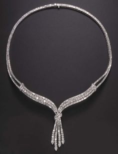 AN ELEGANT DIAMOND NECKLACE Of V-shaped design, suspending at the front a circular and baguette-cut diamond tassel, enhanced by pear-shaped diamond terminals, gathered by a baguette-cut diamond scroll motif, to the circular and baguette-cut diamond three-row surmount, joined by similarly-set scrolled shoulders to the baguette-cut diamond twin-line backchain, mounted in platinum, 17 ins. 20th century or 20th century style, post 1950 Elegant Diamond Necklace, Antique Diamond Necklace, Jewelry Set Design, Heart Necklace Diamond, Solitaire Pendant Necklace, Diamond Necklace Set, Diamond Jewelry Necklace, Diamond Jewelry Designs, Necklace Diamond