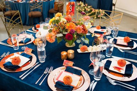 Low centerpiece on navy blue velvet linen with burnt orange, red, and peach dahlias, for a fall wedding reception with rose gold chargers and a orange dahlia on each napkin  | Flora Nova Design Blue Flower Centerpieces, Navy Blue Groomsmen, Blue Orange Weddings, Orange Centerpieces, Blue Groomsmen, Burnt Orange Bridesmaid Dresses, Burnt Orange Wedding, Orange Wedding Colors, Orange Wedding Invitations