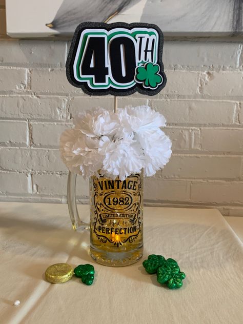 Dollar store mug, flower, shamrock & gold coins. 
Black vinyl and stencil on cricut
40th sign made out of layered card stock using cricut. Filled with colored water and added clear water beads from Craft store. Aged To Perfection Party Centerpieces, 40th Birthday Ideas For Men Centerpieces, 40th Bday Centerpieces For Men, Masculine Birthday Party Centerpieces, 50th Centerpieces For Men, Men Birthday Centerpiece Ideas, 30th Birthday Centerpieces For Men, 60th Birthday Centerpieces For Men, Beer Centerpieces For Men