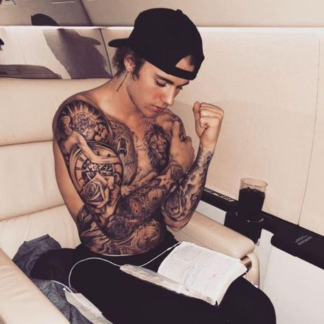 Singer-songwriter Justin Bieber's latest proclamation of his Christian faith is a photo he posted to his Instagram account over the weekend. It shows him sitting down on an airplane seat, shirtless, with an open Bible on his lap. Man With Tattoos, Justin Bieber, A Man, Tattoos, Reading