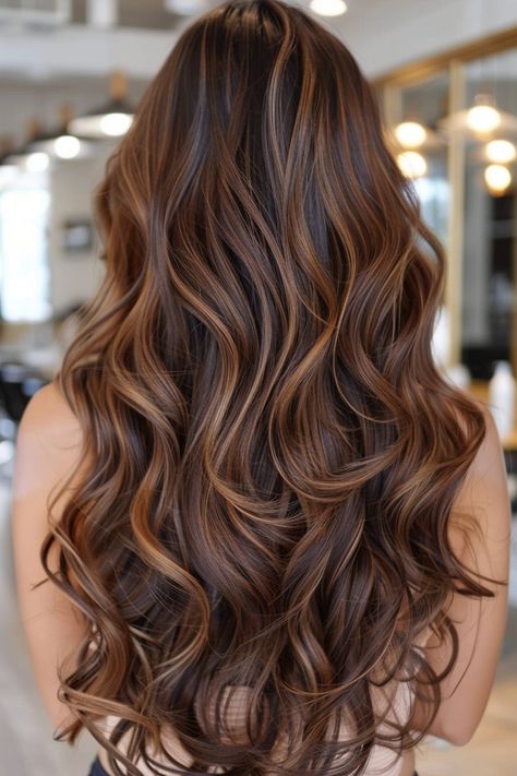 Long, wavy hair with rich brown and caramel highlights in a salon setting. Carmel Red Blonde Balayage, Blonde Hair Brown Highlights Caramel, Golden Brunette Highlights, Caramel Highlights On Dark Hair Wavy, Dark Brown Hair Balayage Auburn Caramel Highlights, Dark Golden Balayage, Brown Carmel Balayage Hair, Cooper Caramel Hair, Dark Hair Honey Highlights