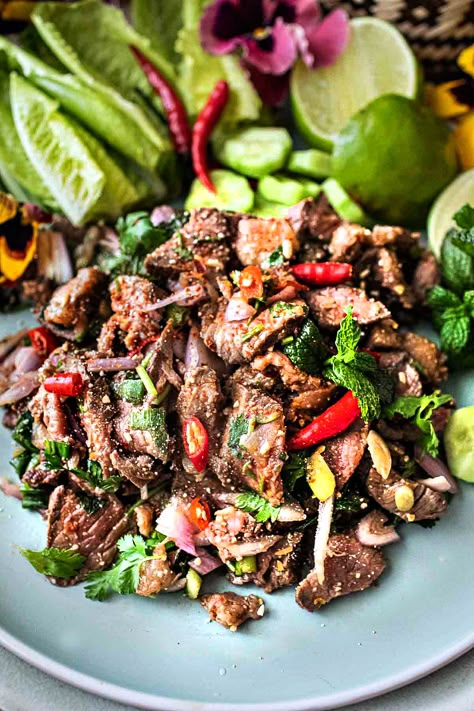 This authentic Thai beef larb recipe is a super tasty and popular dish from Isaan (Northeastern )Thailand. It's a flavorful salad made with near-raw, thinly sliced beef. This tasty Thai larb has a wonderful assortment of fresh herbs that bring out the bold, addictive flavors. It's an easy recipe, and it's extra healthy! #beeflarb #beeflaab #beeflarbrecipe #authenticbeeflarb #thailarb #thailaab #thailaabrecipe #authenticlaabrecipes Thai Food Salad, Spicy Beef Salad Thai, Thai Laab Recipe, Nam Tok Beef Salad Recipes, Thai Chicken Larb, Beef Larb Recipe Thai, Thai Beef Marinade, Larb Recipe Thai Authentic, Laab Salad Recipe