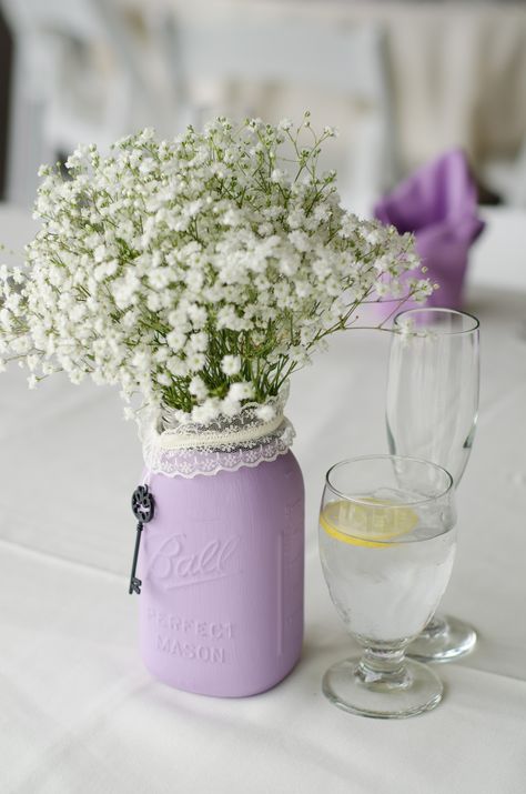 A simple bunch of babies breath in a lavender painted mason jar. Mason Jars With Lavender Flowers, Lilac Mason Jar Centerpieces, Lavender Birthday Party Ideas Simple, Lavender Mason Jar Centerpiece, Lavender Butterfly Baby Shower Ideas, Lilac Bridal Shower Ideas, Lavender Bridal Shower Ideas, Lavender Baby Shower Ideas, Lavender Baby Showers