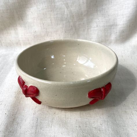 Cute bow bowl 🎀 #pottery #potteryart #bow #bowl #clay #claybowl #claybows #redandwhite #🎀 #stoneware #ceramics #cuteceramics #ceramicart #ceramicsofinstagram #pottersofinstagram #tending #aesthetic #new Christmas Ceramics Bowl, Small Pottery Bowl, Small Ceramic Bowl Ideas, Aesthetic Clay Bowl, Pinch Bowls Ideas, Clay Bowls Aesthetic, How To Make A Bowl Out Of Clay, Bowl Clay Ideas, Ceramic Yarn Bowl Ideas