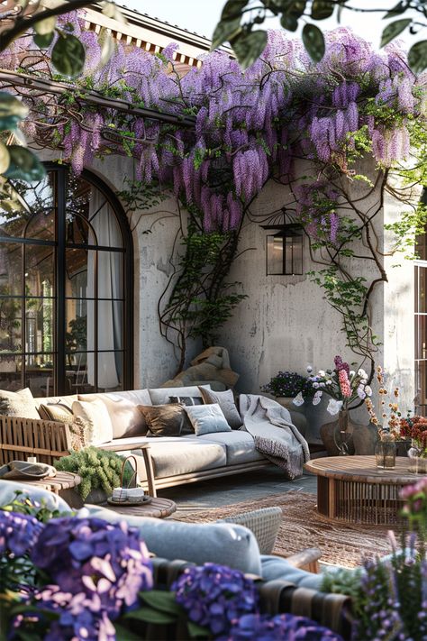 Cascade of Wisteria • A verdant living tapestry drapes elegantly over the pergola, wisteria blooms in a vibrant cascade of lavender • Beneath, a plush array of cushions and throws adorn the outdoor sofa, inviting leisurely afternoons • Time stands still in this tranquil alcove, where rustic charm meets refined comfort • The laughter of blooms and whispers of leaves create a melody, while the soft glow of natural light completes this picturesque retreat. House With Wisteria, Pergola Wisteria, Nature Backyard, Wisteria Arbor, Wisteria Pergola, Cushions And Throws, Time Stands Still, Wildflower Garden, Backyard Inspo