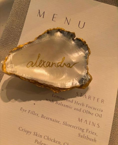 Hi there!  I'm honoured to be considered to be part of your special day.  Each oyster shell is meticulously painted with a beautiful pearl paint,  carefully edged with a rich gold and handwritten with your guests names. I personally collect each shell to ensure the highest quality for your event.  I have a few options for your order that you can select below: - Pearl Shell - Your oyster shell painted with pearl paint only.  - Pearl Shell with Name - Your oyster shell painted with pearl paint onl Oyster Themed Party, Wedding Oysters, Oyster Shell Painting, Oyster Wedding Decor, Oyster Name Cards Wedding Ideas, Oyster Name Cards, Oyster Place Setting Wedding, Oyster Shell Seating Cards, Shell Place Cards Wedding