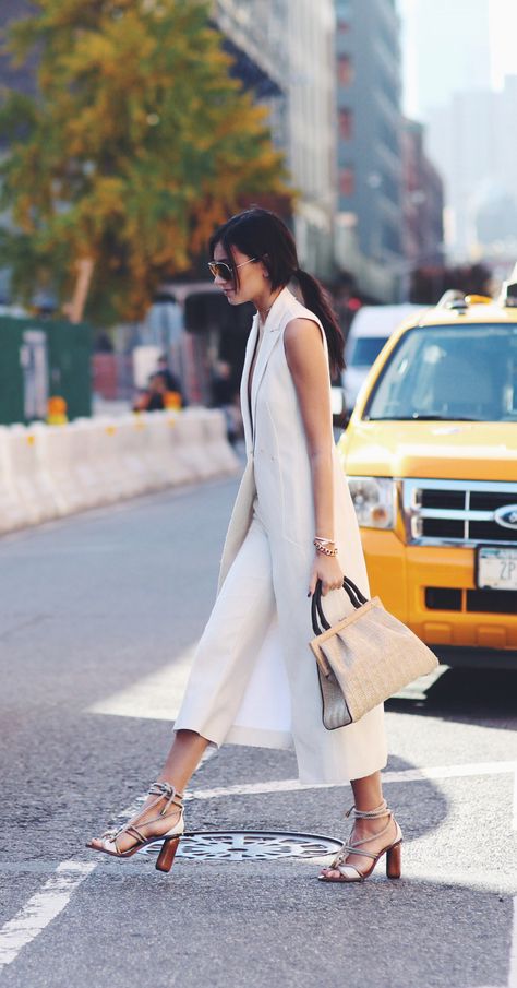 Sleeveless coats are becoming a must have this season! Danielle Bernstein wears this white number with a neutral outfit consisting of white culottes, a beige straw bag, and a pair of gorgeous cream... Long Vest Outfit, How To Wear Culottes, White Culottes, Fashion Kimono, Culottes Outfit, Vest Outfits For Women, Minimalist Moda, Duster Vest, Style Parisienne