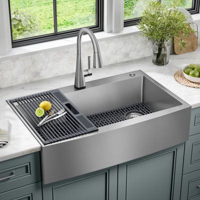 The Delta Lenta Stainless Steel Farmhouse Sink is designed with clean lines and a curved apron front that creates a natural kitchen centerpiece with a clean contemporary aesthetic. Ideal for retrofitting, the top mount design installs as a drop-in sink with any countertop material. Heavy-duty TRU16 gauge stainless steel and SatinSheen finish offers lasting durability and easy maintenance. The sink comes with a grey silicone bottom grid that helps protect the sink surface and a matching over-the- Drop In Stainless Steel Kitchen Sink, Stainless Farmhouse Sink Kitchen, Apron Front Sink Farmhouse, Farm Style Kitchen Sink, Over Mount Kitchen Sink, Drop In Farmhouse Sink With Apron, Farm Sinks In Kitchen, Drop In Sink Kitchen, Kitchen Sink And Faucet Ideas