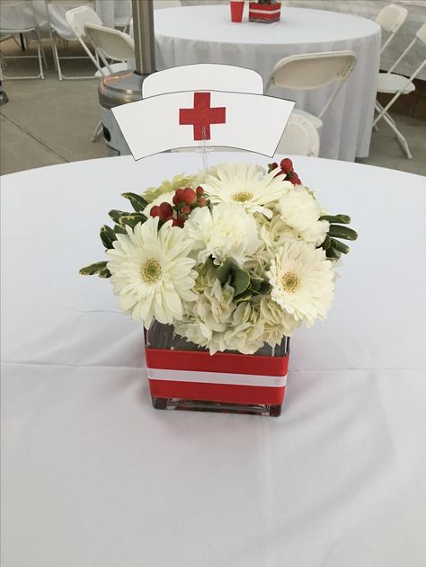 Red and white flowers for nurse graduation theme party! Nurse Flower Arrangement, Nursing School Graduation Party Centerpieces, Nurse Table Decorations, Nursing Party Centerpieces, Retirement Party For Nurse, Nurse Graduation Backdrop, Nurse Retirement Party Ideas Decorations, Nursing Graduation Centerpieces, Nursing Centerpieces Graduation