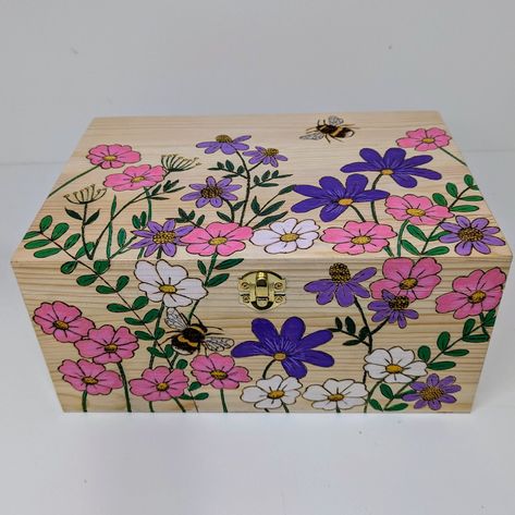 Large pine storage box handburnt using pyrography with pretty wildflowers and bees and coloured using acrylics. Perfect for storing treasured items or photos. Part-lined with pink felt. Just added to my shop. Link to my shop in my bio if you fancy a peek 👀 #pyrographyuk #pyrography #memorybox #keepsakebox #storage #homedecoruk #woodengifts #madeindevon #handmadeuk #giftideas #weddinggifts #newonfolksy #folksyhq #woodenboxes Wooden Treasure Box Painting Ideas, Painted Boxes Ideas, Painted Box Ideas Simple, Painted Jewelry Boxes Diy, Wood Box Painting Ideas, Wooden Box Painting Ideas, Box Painting Ideas, Pretty Wildflowers, Diy Jars