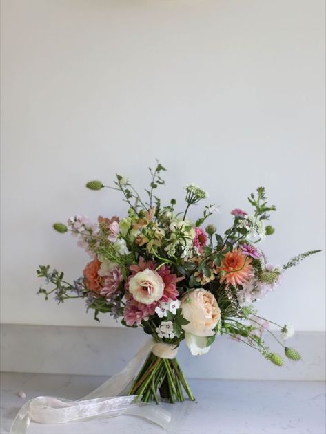 Peach toned bridal bouquet with trailing ribbons sitting on a marble block. Summer Wedding Flowers Uk, March Wedding Flowers Uk, Simple Wedding Bouquet Colorful, Wedding Bouquets No Roses, Garden Flowers Wedding Bouquet, Wedding Flowers March, Wedding Flowers Romantic, Lavender In Bouquet, English Garden Bridal Bouquet