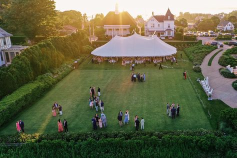 Drone shot of outdoor, tented Ocean House wedding in Watch Hill, Rhode Island. Guests enjoying cocktail hour on the lawn at sunset Floral Design: Hana Floral Design @hanafloral Photographer: Clark Brewer https://www.clarkbrewerphotography.com Small Backyard Party, Sperry Tents, Puglia Wedding, Sperry Tent, Wedding Marquee, Oyster White, Rhode Island Wedding, Pennant Flags, Tent Reception