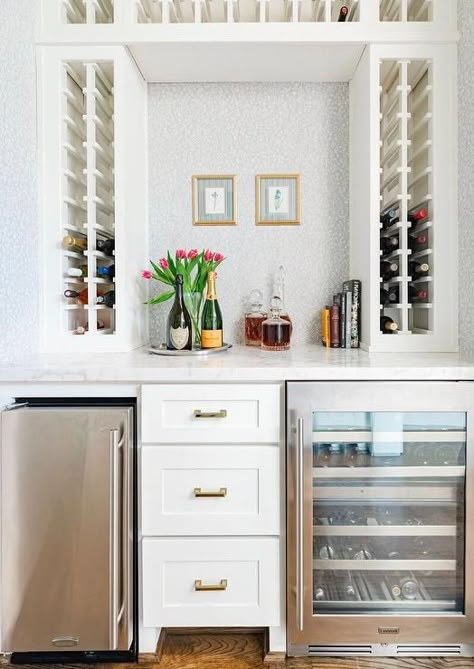 Built-in wine racks frame a white and gray wallpapered wall holding gold framed art over white drawers flanked by a stainless steel beverage fridge and a glass-front wine fridge. Wet Bar Cabinets, Fridge Design, Built In Wine Rack, Interiors Photography, Outdoor Kitchen Cabinets, Beverage Fridge, Kitchen Finishes, Wine Wall, Wine Rack Wall