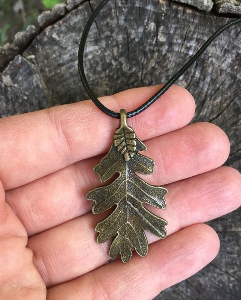 This necklace is inspired by the oak leaf pendants worn by the Araluen rangers in Ranger's Apprentice series. A bronze oak leaf is worn by Ranger apprentices (silver leaf is a symbol of the active Rangers and gold - of the retired Rangers). The oak is a common symbol of strength and endurance.  The large (~2"x1") oak leaf pendant is suspended on a 25" long black waxed cord with a matching black cord lock (adjustable length - can be shortened as needed without taking the necklace off). Alternativ Rangers Apprentice Oak Leaf, Rangers Apprentice Costume, Oakleaf Necklace, Ranger's Apprentice, Halloween Costume Jewelry, Oak Leaf Necklace, Rangers Apprentice, Boho Witch, Forest Necklace