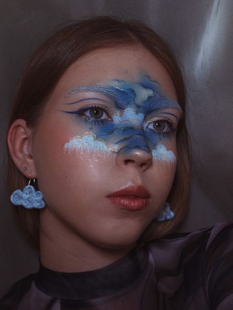 In the middle of the face are drawn blue clouds, that are outlined in gold Weather Makeup Looks, Cloud Eye Makeup, Rain Makeup, Surrealist Ball, Cloud Makeup, Sky Makeup, Makeup Painting, Air Makeup, Cloud Costume