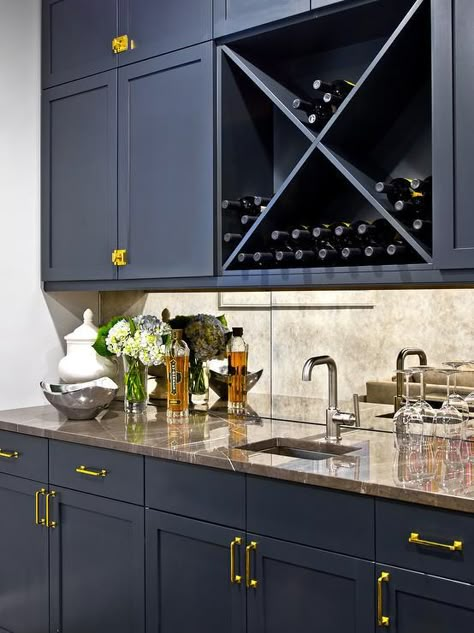 Glam wet bar boasts blue shaker cabinets adorned with brass pulls and knobs paired with brown marble countertops and an antiqued mirrored backsplash, A square wet bar sink and a satin nickel bar faucet stands under a navy blue crosscut wine rack. Blue Wet Bar, Antique Mirror Backsplash, Wet Bar Cabinets, Blue Shaker Cabinets, Backsplash Herringbone, Bar Countertops, Farmhouse Backsplash, Beadboard Backsplash, Mirror Backsplash