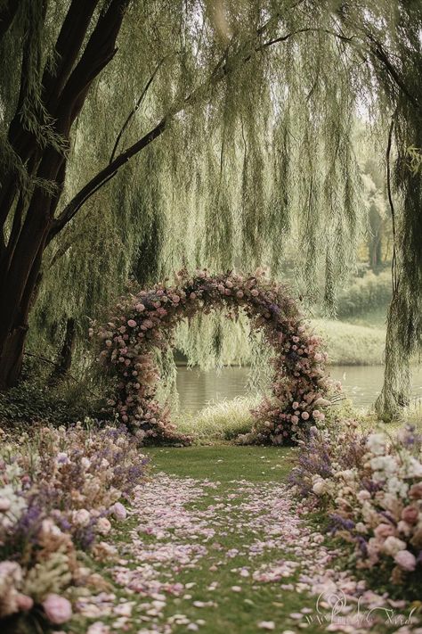 Floral archway by a tranquil pond under lush trees. Unearth a treasure trove of vibrant and whimsical ideas to sprinkle your spring wedding with the season’s unique charm and charisma. Wedding Under Weeping Willow Tree, Outdoor Fairy Wedding Ideas, Wedding In Backyard Ideas, Outside Wedding Aesthetic, Ethereal Wedding Arch, Forest Fairy Wedding Theme, Spring Fairy Wedding, Pond Wedding Ideas, Moongate Wedding