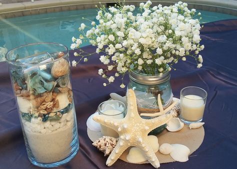 Baby's breath in a mason jar with seashell accents designed by www.flowergirlzinc.com Seashells Centerpieces, Seashell Vase Centerpiece, Sea Shell Wedding Table Decor, Sea Theme Flower Arrangements, Shark Wedding, Sea Shells In Glass Vases, Beach Theme Wedding Centerpieces Budget-bride.shop, Wedding Shower Food, Beach Centerpieces