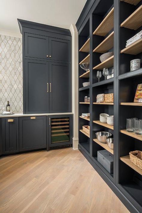 Chic black pantry boasts a diagonal pattern wood floor fitted with a wall of black open cabinetry with blond wood shelves, while blue shaker cabinets donning brass pulls are fitted over a built-in glass front wine fridge. Benjamin Moore Soot Kitchen Cabinets, Open Pantry Wall In Kitchen, Benjamin Moore Soot Paint, Soot By Benjamin Moore, Soot Benjamin Moore Cabinets, Kitchen Cabinet With Shelves, Pantry Paint Colors Open Shelving, Benjamin Moore Soot Cabinets, Open Kitchen Shelving Ideas Wall Shelves