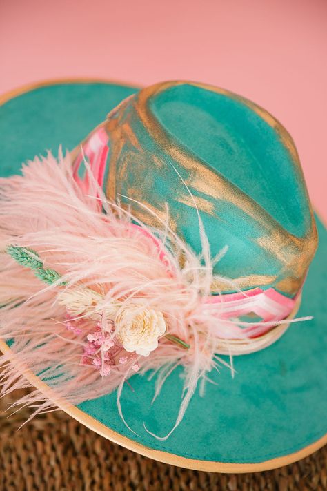 Get ready to wrangle some compliments with The Floral Tennis Rancher Hat! This turquoise beauty boasts gold accents, a striking pink aztec ribbon band, and a pink sequin Tennis patch on the back. Add in a splash of color with the pink feather combo and you've got yourself a truly unique accessory. This hat is ONE OF A KIND, created by our owner Stephanie. To receive item quicker, expedited shipping is available at checkout. Cowgirl Hat Ideas, Painted Hats For Women, Cowboy Hat Crafts, Custom Cowboy Hats, Funny Trucker Hat, Pretty Hats, Hat Bands, Judith March, Felt Cowboy Hats