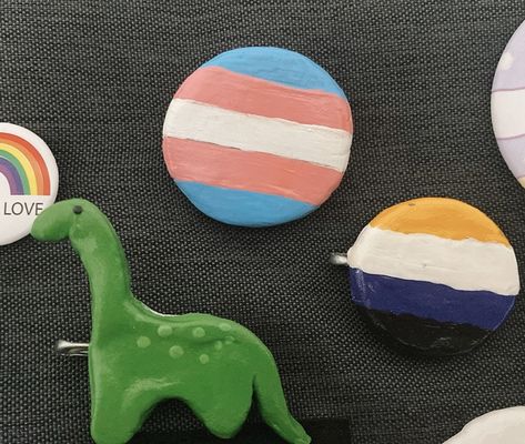 Trans and non Binary flag and lil dino🦕 Trans Pins And Patches, Trans Pin, Charlie Core, Random Accessories, Non Binary Flag, Non-binary Flag, Clay Pins, Button Ideas, Accessory Ideas