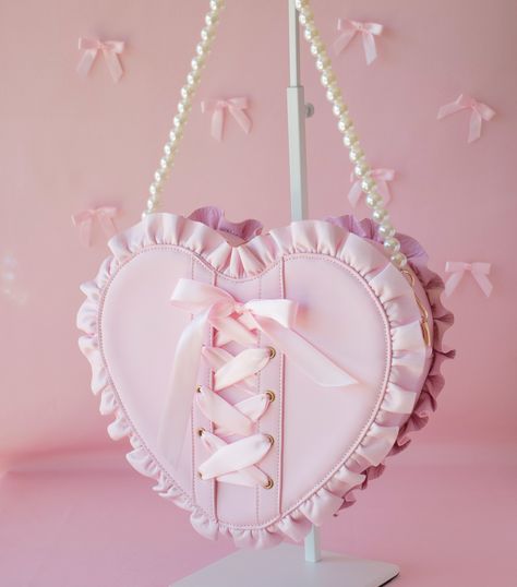 ♡ The Pink Dahl Bag ♡ Embrace the whimsical world of balletcore with our enchanting light pink heart-shaped bag. Adorned with delicate ruffles and a charming lace-up ribbon detail featuring a sweet bow, this accessory is the epitome of coquettish elegance. Unleash your inner romantic with this original design that merges ballet-inspired grace with a touch of flirtatious charm. This bag is a LoveAprilMoon original including its custom heart shaped metal zipper pulls and heart details. With its ad Cute Kawaii Handbags, Heart Shaped Leather Bag, Light Pink Accessories, Little Bag Of Love, Kawaii Objects, Alt Accessories, Heart Backpack, Funky Bags, Ribbon Bag