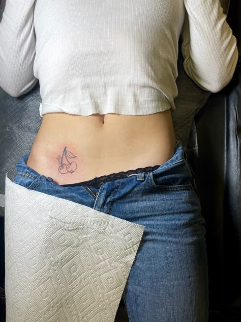 Minimalist Stomach Tattoo, Cherry Tattoo On Hip Bone, Small Cherry Tattoo On Hip, Cherry Tattoo Placement Ideas, Cherry Finger Tattoo, Cherry Hip Tattoo, Cherry Tramp Stamp, Cherry Tattoo On Bum For Women, Cherry Tattoo Black