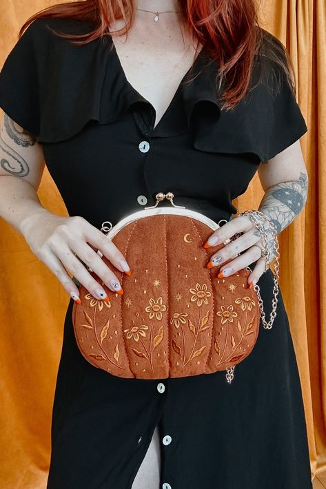 Our absolutely gord-geous Pumpkin purse is here to help you serve fall vibes. The outside is made from soft, velvet fabric. Lightly padded, it has a cuddly, squishy feeling. Not something one normally looks for in a purse, but trust me, you will love it. With delicately embroidered with yellow flowers, stars, and a moon on both sides, this witchy handbag is sure to become part of your regular outfit rotation. #vintagefashion #purses #handbags #fallfashion Witchy Handbag, Cool Purses, Outfit Rotation, Embroidered Pumpkin, Novelty Purses, Evil Witch, Leather Credit Card Holder, Unique Purses, Sewing Box