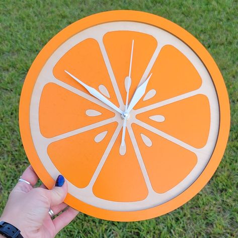 "NOTICE: We are having an issue with our clock hand supplier so, the clock hands may vary just slightly from what is shown. They will still be silent but have less taper to the ends of the hands.  Brighten up your kitchen with this orange slice clock! Made from maple wood and measures about 10.5\" tall. Quality silent sweep Clock movement with white hands." Pink And Orange Kitchen Decor, Food Themed House Decor, Orange Themed Kitchen, Food Themed Kitchen Decor, Fruit Kitchen Decor Themes, Fruit Themed Decor, Orange Fruit Decor, Fruit Home Decor, Fruit Themed Kitchen