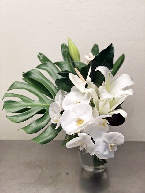 Phalaenopsis orchids, anthirium, and lilies with anthirium and monstera leaf bridal bouquet for a tropical themed wedding. Tropical Orchid Centerpiece, Modern Tropical Bouquet, Monstera Wedding Bouquet, White Tropical Bouquet, Orchid Wedding Decor, Monstera Bouquet, Orchid Wedding Centerpieces, Leaf Arrangements, Orchid Centerpieces Wedding