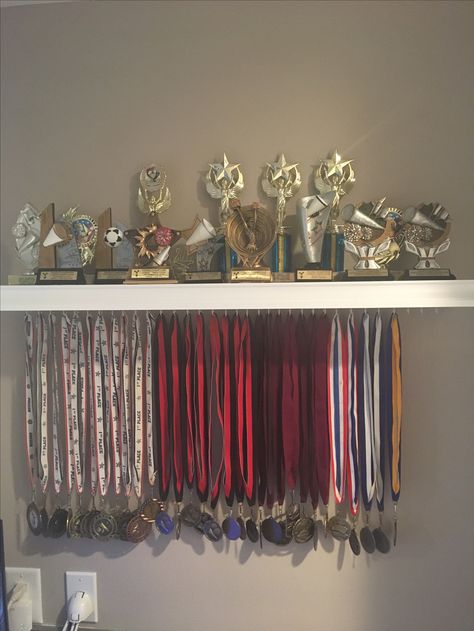 Medal and trophy display. Trophy Stand Design, Football Medal Display Ideas, Medals And Trophy Display Ideas, Trophy Organization Ideas, Cheer Trophy Display Ideas, Medal Picture Ideas, Trophies And Medals Aesthetic, Dance Trophy Display Ideas, Dance Medal Display Ideas