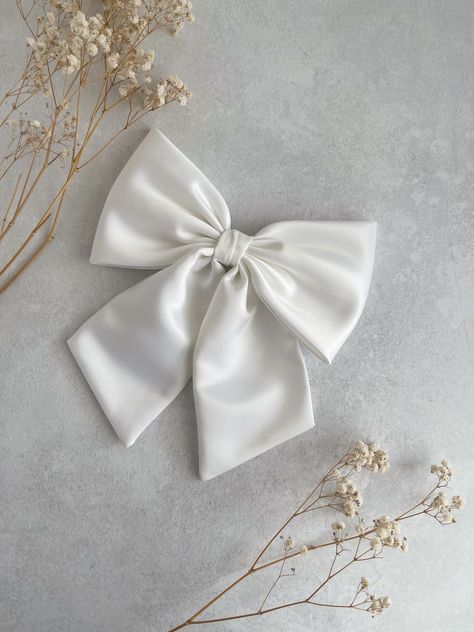 Large and Luxurious White Duchess Satin with tails hair bow.  This oversized hair bow is an ideal hair accessory for wearing to a special occasion, absolutely perfect as bridal hair bow for a wedding, hen party or evening reception!  It will also make a great "gift for girl." They are handmade with love and care from  high quality fabric in our studio in England. The bow measures  8" in width appx  12 cm or 4 3/4" in height  Tail is 18 cm or 7" long approximately  📍Attachments :  ✅Barrette  ✅Co Black Zip Up Hoodies, Bridal Bow, White Hair Bow, Large Hair Bow, Giant Bow, Evening Reception, Disney Bows, White Hair Bows, Large Hair Bows