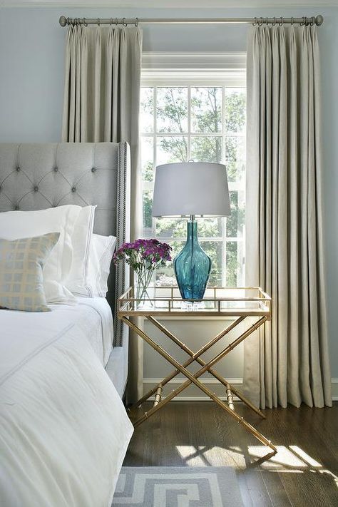 Gray French linen pleated curtains drape a bedroom window against light blue walls next to a gold bamboo tray table. Curtains For Light Blue Walls, White Changing Table, Curtains Blue, Bedroom Details, Window Table, Silk Drapes, Light Blue Walls, Grey Interior Design, Drapes And Blinds