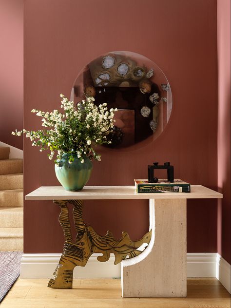 This raspberry rust shade by Benjamin Moore, called Fading Twilight, sets a dramatic mood in an entrance hall. The vintage console, mirror with sliced agate by Chen Chen & Kai Williams and the bold artwork by Sandra Ramos are pulled together by the strength of the wall colour. Benjamin Moore Fading Twilight, Entrance Hall Colours, Colourful Entrance Hall, Bold Entryway Colors, Fading Twilight Benjamin Moore, Rust Hallway, Rust Wall Color, Hall Wall Colour, Rust Walls