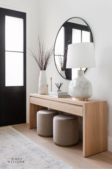 Flooded with natural light, this entryway feels fresh and inviting. The stone lamp adds a touch of elegance, while the wood console table keeps essentials like keys and sunglasses neatly tucked away. The two suede stools double as a stylish detail and a practical spot for putting on shoes. Floating Entrance Table, Entryway Ideas Functional, Entry Table With Stools, Key Table Entry, Entryway Console Table Decorating Modern, Console Table Decorating Modern, Entryway Seating Ideas, Condo Entryway Ideas, Entryway Console Table Decorating