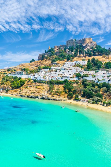 Castle ruins on a hilltop dotted with white villas leading down to yellow-sand beach and turquoise water. Lindos Greece, Lindos Rhodes, Dodecanese Islands, Rhodes Island, Cities To Visit, Greece Islands, Coastal Cities, Holiday Villa, Acropolis