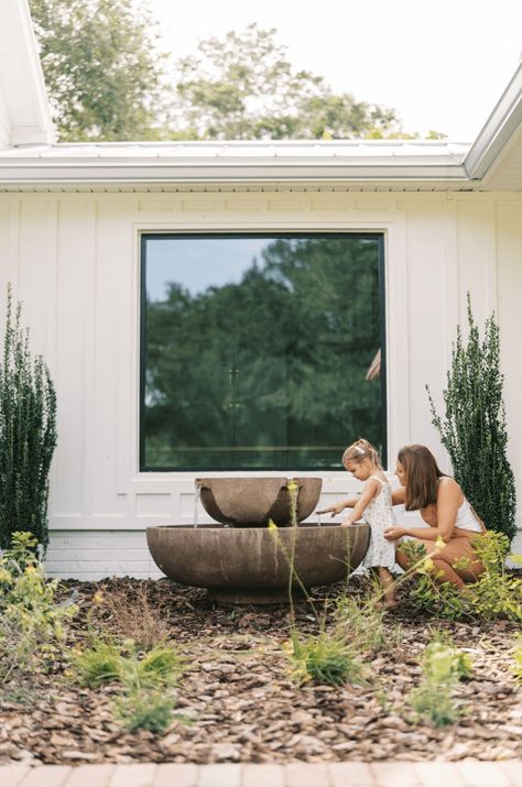 A fountain in a front yard Front Yard Centerpiece Landscaping Ideas, Front Yard Water Fountain, Front Yard Landscaping Ideas With Rocks Water Fountains, Fountain Front Yard, Farmhouse Water Fountain, Large Pot Fountain, Ranch Fountain Ideas, Outdoor Rock Fountain, Circle Driveway Water Fountain