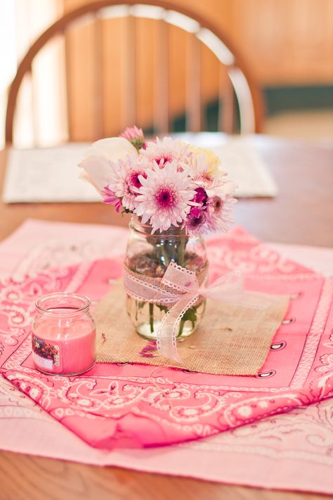 Simple pink bandanas (Michaels) with a piece of burlap on it (Amazon), a mason jar wrapped with a strip of burlap and ribbon, and some assorted flowers. These were the table centerpieces. #vintagecowgirl #cowgirlparty Pink Cowgirl Party Centerpiece, Cowgirl Hat Centerpiece, 1st Rodeo Centerpieces Pink, Cowgirl Themed Centerpieces, Rodeo Birthday Party Centerpieces, Pink Western Centerpiece Ideas, Bandana Centerpiece Ideas, Pink Country Birthday Party, Cowgirl Table Centerpieces