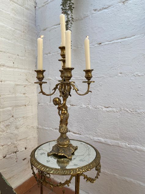 This antique French candelabra is a stunning piece of furniture that will add a touch of elegance to any room. The candelabra is handmade and original, manufactured in France or Spain. Measuring 18 inches in height and 10.5 inches in width, it is suitable for use as a table centerpiece or in an entryway, foyer, living room, lounge, or dining room. The candelabra is in a Louis XV style and features a cherub subject, making it a perfect addition to any decorative collectibles collection. It is an Candleabras Dining Table, Candelabra Decor, French Candlesticks, Botanical Aesthetic, Candelabra Centerpiece, Foyer Living Room, Dark Botanical, Living Room Lounge, Shop Light