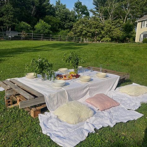 outdoor graduation party setup with charcuterie board and plating; wooden pallets with table cloth and pillow decorations Picnic With Pallets, Picnic Aesthetic With Table, Wooden Pallet Picnic, Picnic In Woods, Picnic Table Aesthetic, Outdoor Picnic Setup, Graduation Party Setup, Pallet Table Outdoor, Picnic Table Party