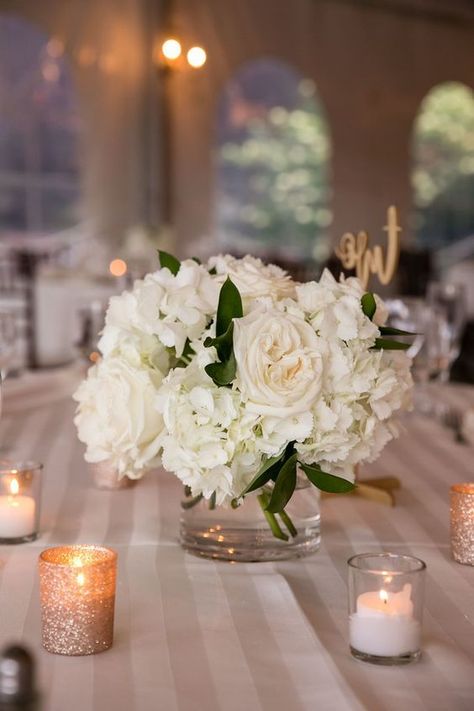 White Roses In Glass Vase, Low White Rose Centerpiece, One Vase Wedding Centerpiece, Small Centerpieces With Candles, Small White Centerpieces Simple, White Rose Bouquet Centerpiece, Simple Hydrangea Centerpiece Wedding, Round Flower Centerpieces, Bridal Bouquet As Table Centerpiece