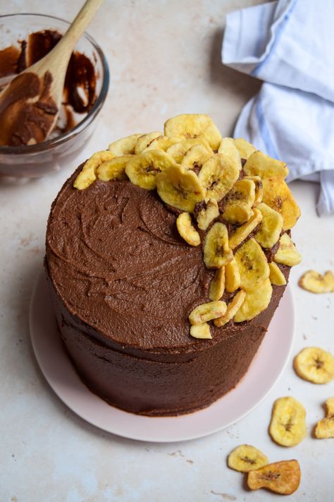 Overhead shot of a cake covered in chocolate frosting with dried banana chips decorating the top on a stone background. Banana Layer Cake, Dried Banana Chips, Raspberry Pistachio, Chocolate Roulade, Birthday Cake Decorating Ideas, Dried Bananas, Chocolate Cream Cheese, Cake Decorating Ideas, Celebration Cake